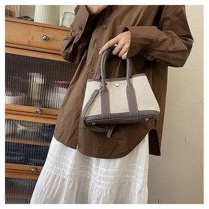 Close-up of minimalist PU tote with round handles, metal snap closure and adjustable strap