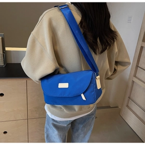 Modellansicht der Rückseite einer kleinblauen Nylon-Umhängetasche mit breitem Gurt