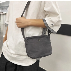 Detailed view of dark grey canvas crossbody bag with silver metal snap button pocket