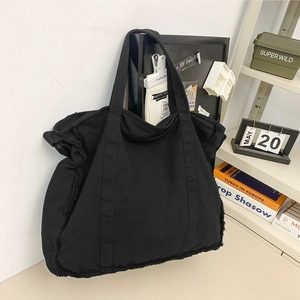 Large black canvas tote bag with trendy raw edges and fringe details for casual wear
