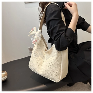 Detail of cream canvas tote bag with floral lace embroidery and a decorative lace bow