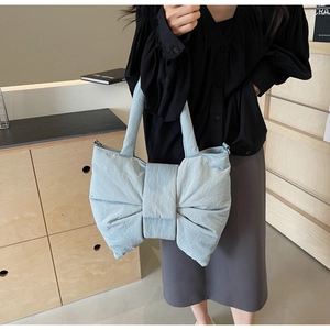 Close-up of a light blue oversized bow-shaped tote bag made of lightweight pleated fabric