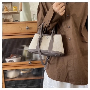Detail of beige canvas and grey leather tote bag with round metal snap button