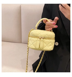 Detailed close-up of quilted PU leather handbag with gold chain strap in light yellow