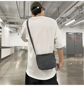 Detail view of charcoal gray canvas crossbody bag with adjustable strap on model