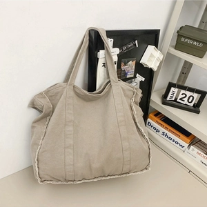 Khaki large canvas tote bag with raw frayed edges in a minimalist lifestyle setting