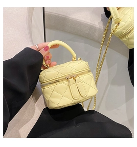 Detail of light yellow quilted PU leather mini trunk bag with gold chain strap