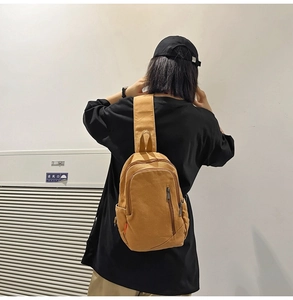Detail view of the khaki canvas crossbody bag worn by a model in casual workwear style