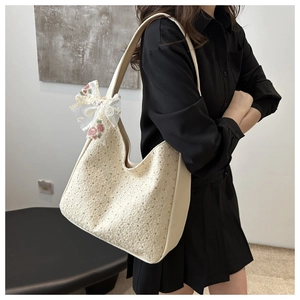 Detailed close-up of cream canvas tote bag with floral lace texture and bow charm