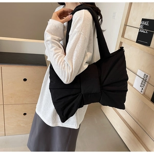 Close-up of oversized bow detail and soft texture on black nylon tote shoulder bag