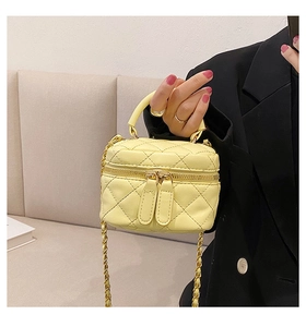 Close-up of pale yellow quilted mini bag with golden chain strap and leather shoulder pad