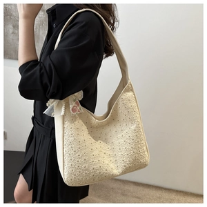 Detail of cream canvas shoulder bag with floral embroidery and lace ribbon bow
