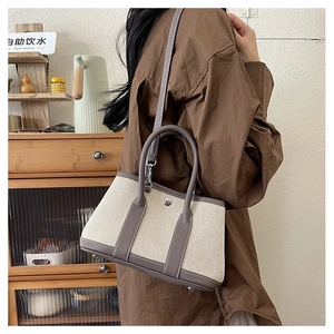 Detail of minimalist canvas and grey leather bag with metal button in cozy home setting