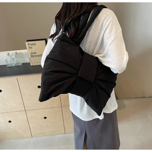 Detailed back view of a large black bow tote bag carried on a shoulder by a model