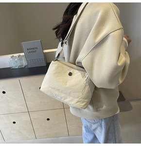Chic beige canvas crossbody bag styled on a model in a minimalist interior setting