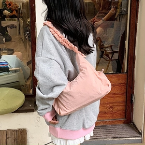 Detail of pink nylon crossbody bag featuring stylish pleated shoulder strap design