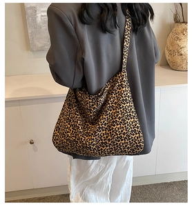 Close-up of a leopard print tote bag with wide shoulder strap in a stylish urban setting