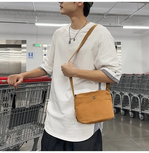 Close-up of ginger yellow canvas crossbody bag with metal ring detail on model