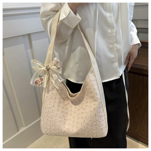 Close-up of canvas shoulder bag featuring pink floral embroidery and lace bow detail