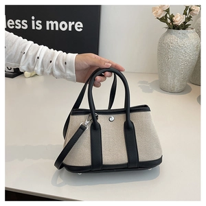 Detail of PU leather and canvas tote bag with contrast stitching and silver hardware