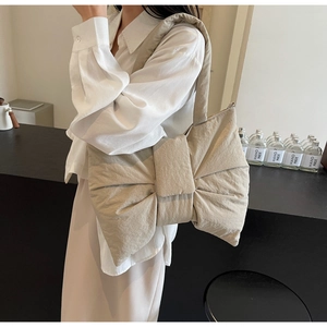 Quilted bow tote bag in beige shown on shoulder with minimalist balletcore aesthetic