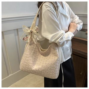 Detail of floral lace embroidery and sheer bow on a beige canvas tote bag