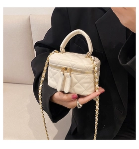 Close-up of a white quilted PU leather crossbody bag with a gold chain strap on a black suit