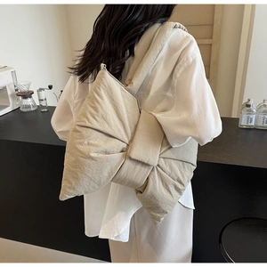 Detail view of oversized bow-shaped tote bag with soft pleated fabric and puffy texture