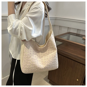 Detailed view of floral lace embroidery on a beige canvas hobo shoulder bag for women