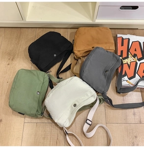 Flat lay of multiple minimalist canvas crossbody bags in five colors with adjustable straps