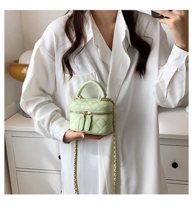 Close-up of mint green quilted mini vanity bag with gold chain strap on shoulder