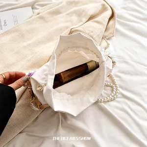 Detail view of white canvas drawstring bag with elegant pearl strap showing interior capacity