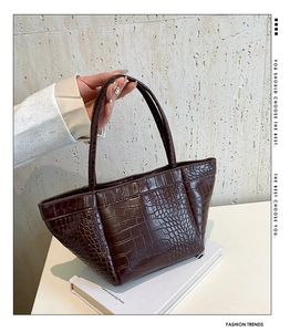 Detail of dark brown tote bag with crocodile pattern and minimalist trapezoid design