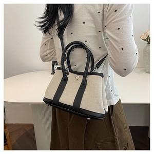 Detailed shot of a canvas and leather tote bag with silver buckle and adjustable strap