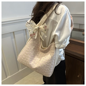 Close-up of cream canvas tote bag with pink floral embroidery and lace bow detail