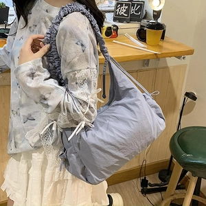 Detail of light blue nylon shoulder bag with ruffled strap and side drawstring bow