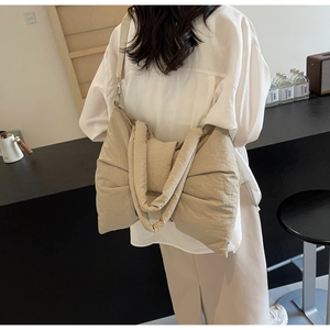 Fashionable beige bow tote bag shown on model in a minimalist modern indoor setting