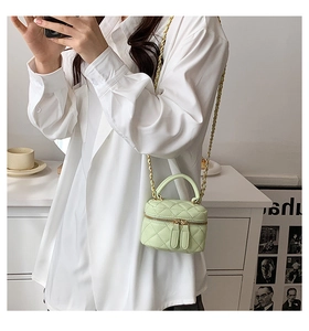 Detail of light green quilted PU leather mini bag with gold chain strap and top handle