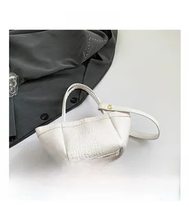 Detail shot of the white PU leather handbag featuring crocodile pattern texture and metal studs