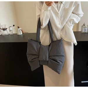 Detail of charcoal grey bow-shaped nylon shoulder bag with wide strap and metallic buckle