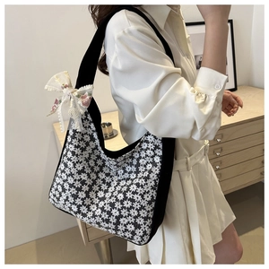 Detailed shot of white lace tote bag with floral embroidery and black trim and ribbon bows