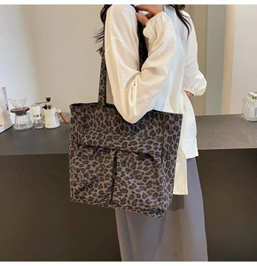 Detail der grauen Canvas-Tragetasche mit Leopardenmuster, Vordertaschen und langen Griffen