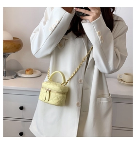 Detail of light yellow quilted PU leather crossbody bag with chain strap on white blazer