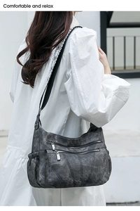 Detail of dark gray washed PU leather shoulder bag with multi-zipper pockets and woven strap