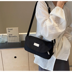 Nahaufnahme der schwarzen Nylon-Umhängetasche mit minimalistischem weißem Etikett