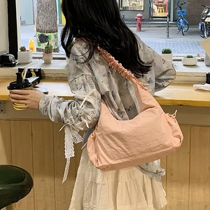 Detail shot of a pink pleated nylon shoulder bag showing ruffled strap and casual texture