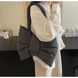 Detail of trendy dark grey oversized quilted bow shoulder bag with a soft puffy texture