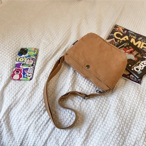 Brown canvas crossbody bag with adjustable strap on white linen in a lifestyle setting