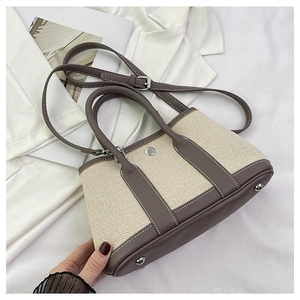 Minimalist beige woven canvas tote bag with brown leather handles and shoulder strap