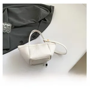 Detail view of white crocodile pattern PU leather handbag with golden rivet accents